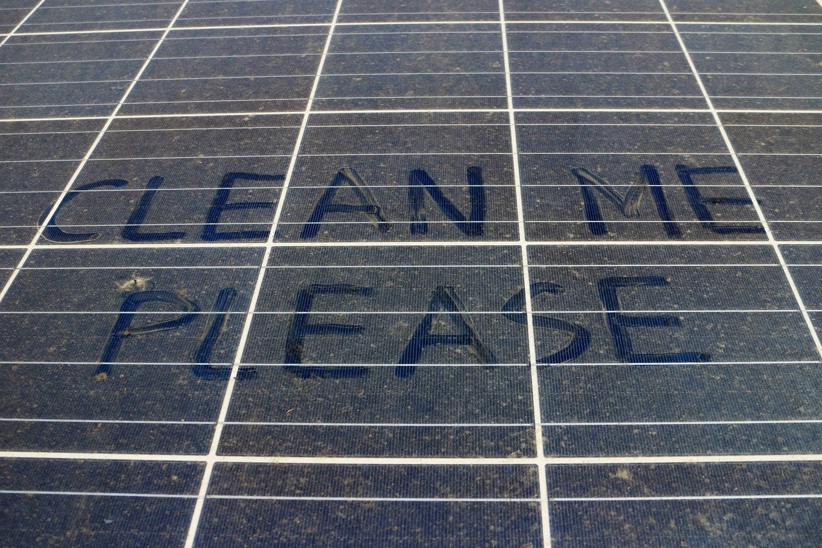 CLEAN ME PLEASE written by finger in the pollen film coating a solar panel