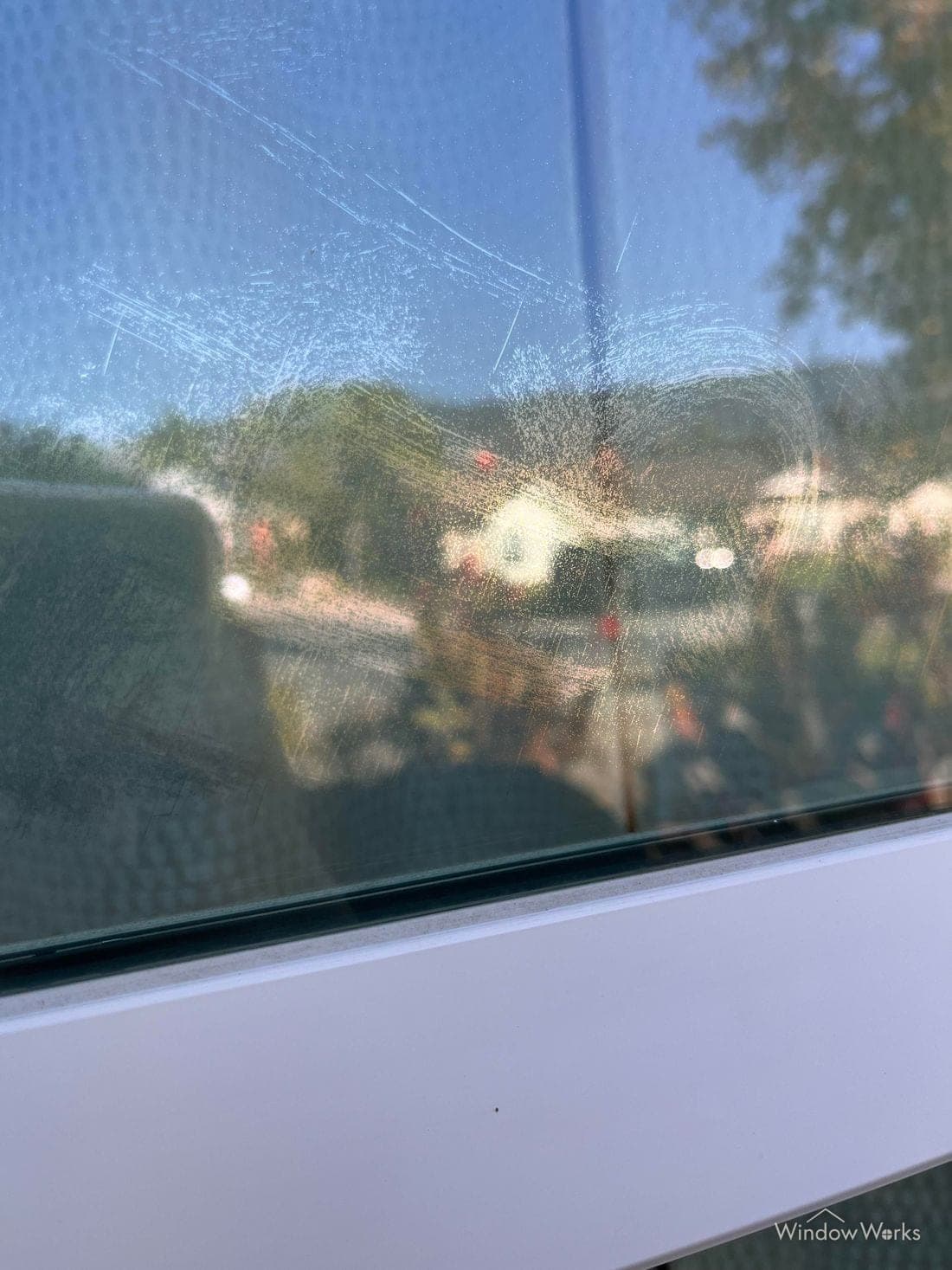 Dense fine scratching and haze across the Low-E coated surface of a window.