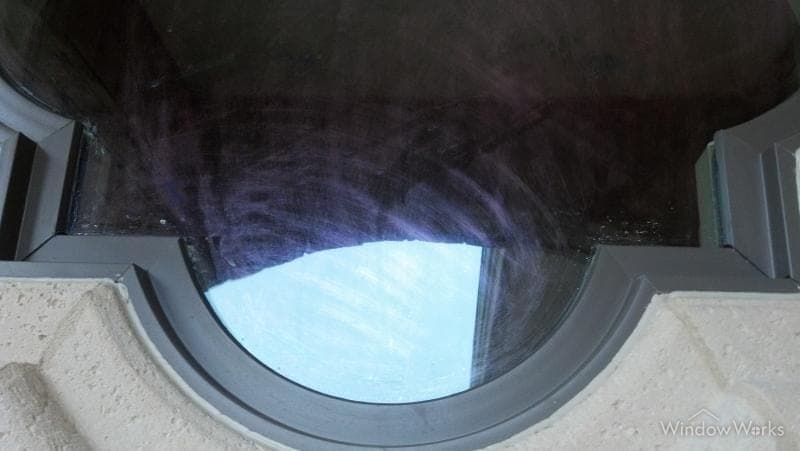 Swirling iridescent scratch marks left in a Low-E coating by an abrasive pad.