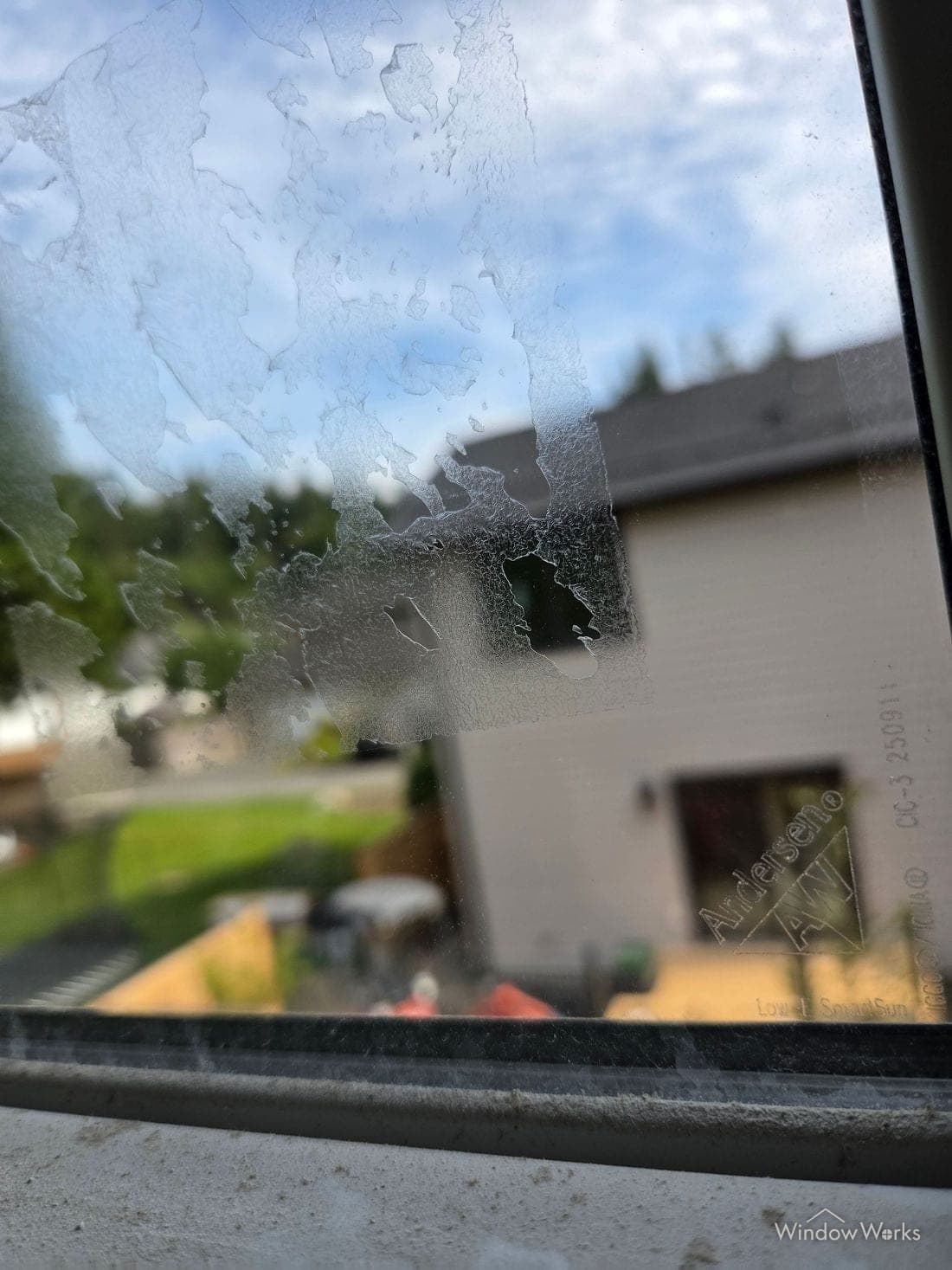 Dried, crazed adhesive residue left on glass where a sticker was peeled off.