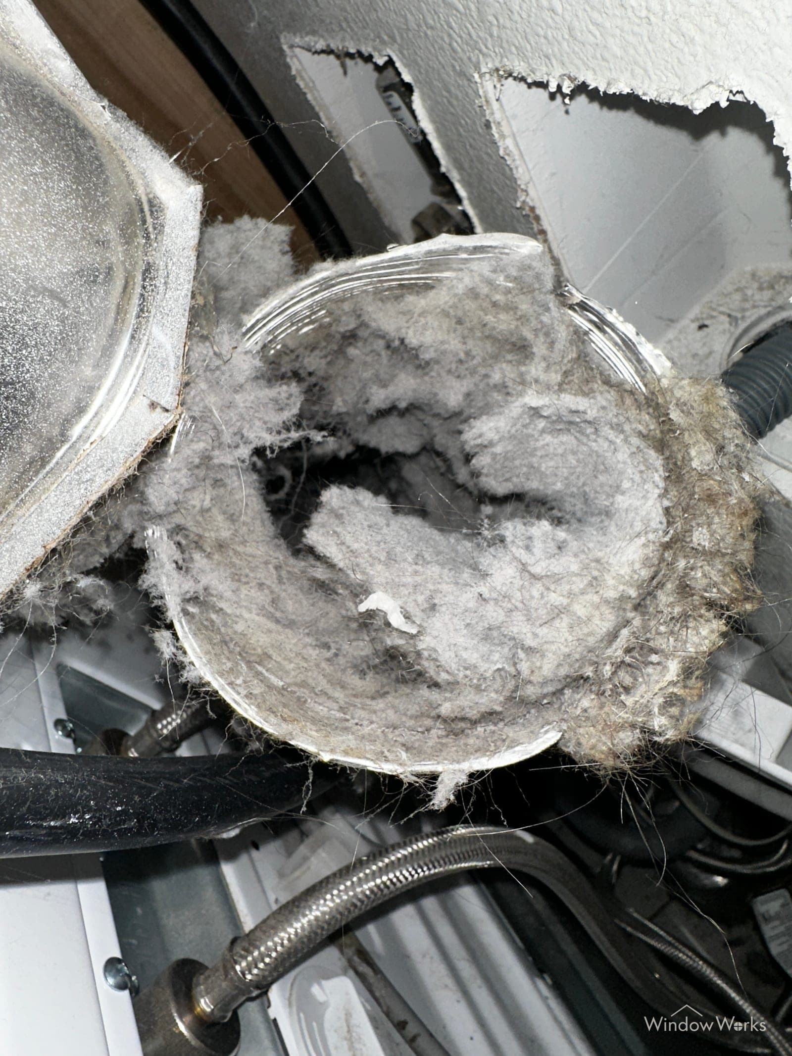 A dryer transition duct behind the machine packed solid with gray lint on an Eastside Seattle job