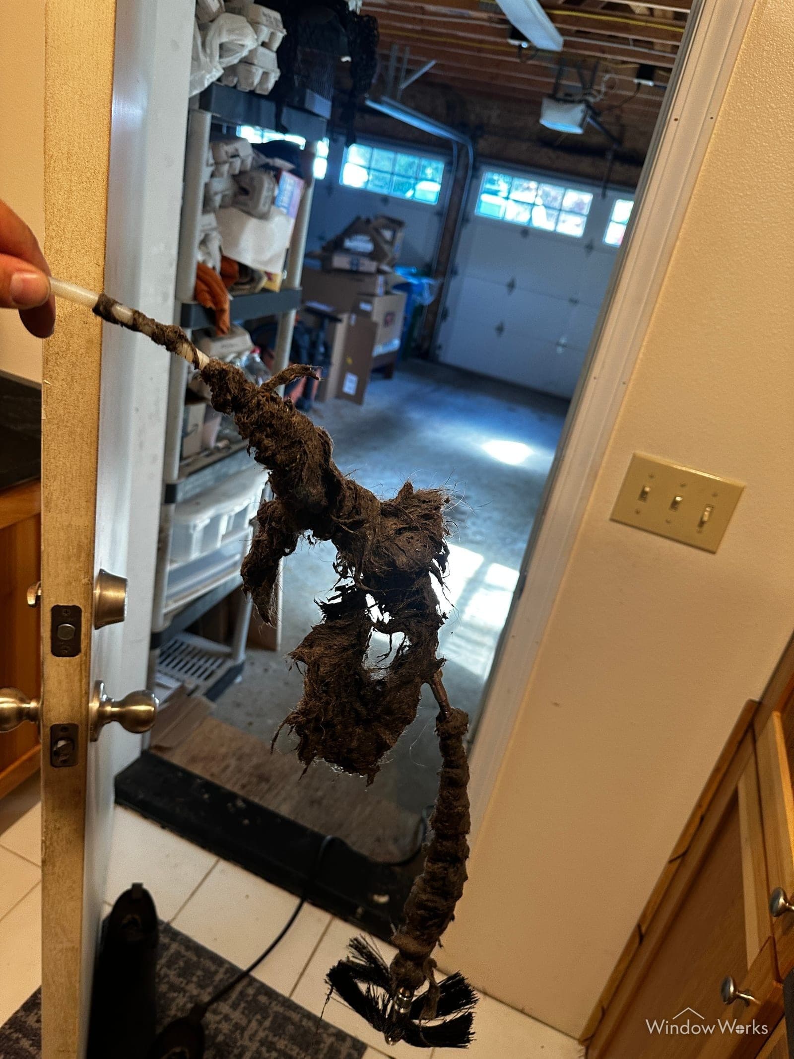 Heavy wet, matted lint pulled out of a dryer vent on the cleaning brush