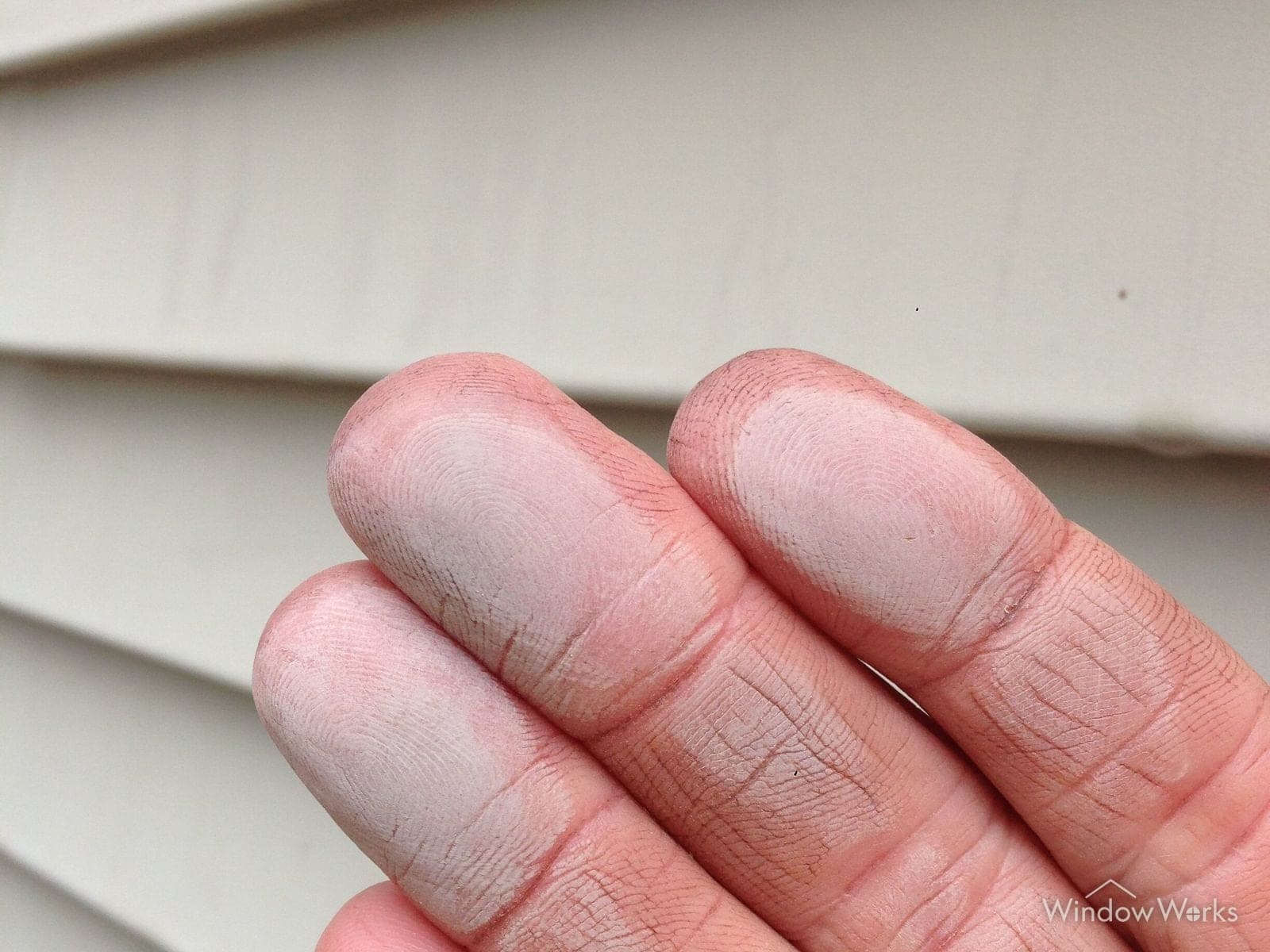 Chalky white oxidation transferred onto a hand wiped across faded painted siding on an Eastside Seattle home