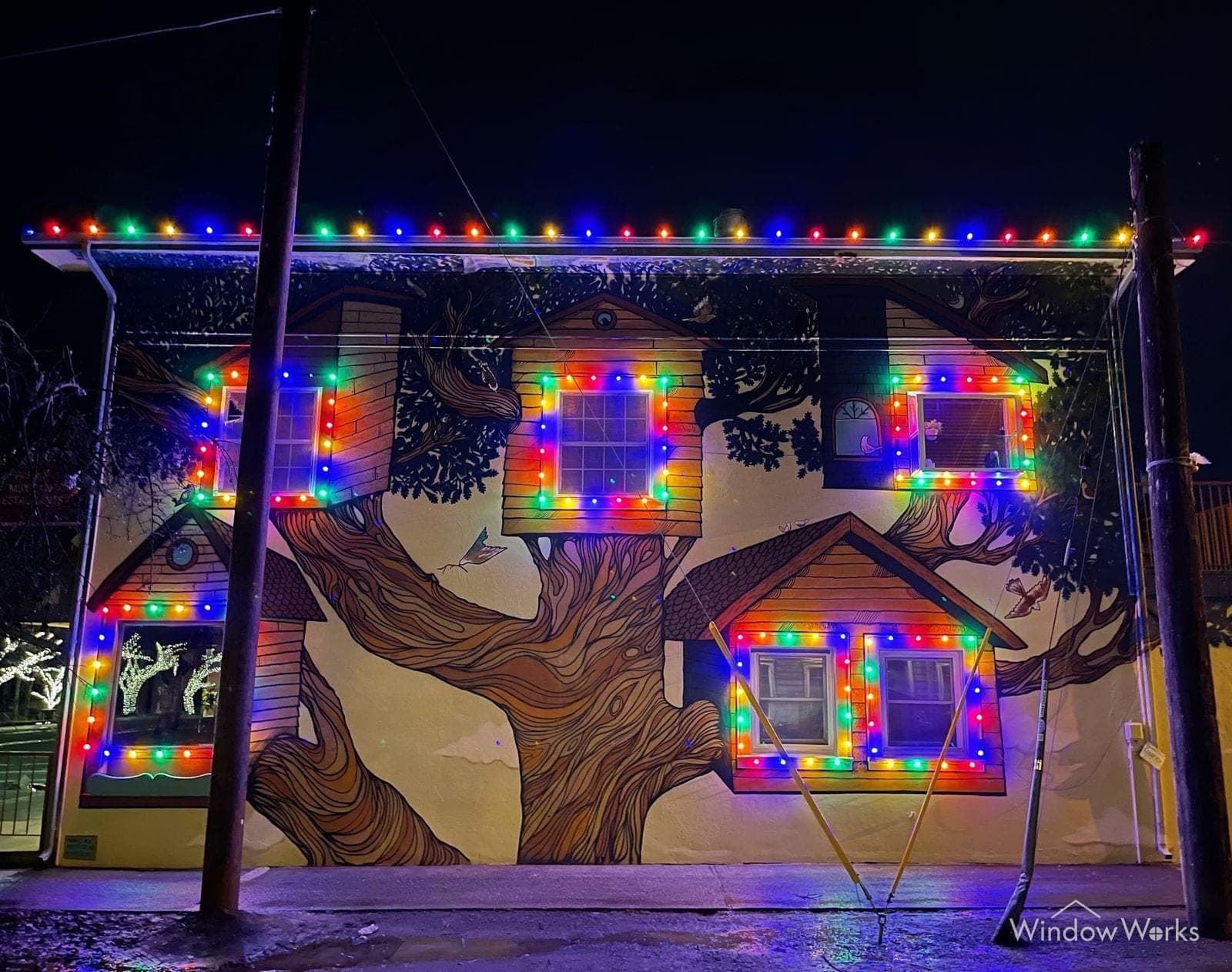 A painted wall mural with real multicolor bulbs framing its windows and rooflines.