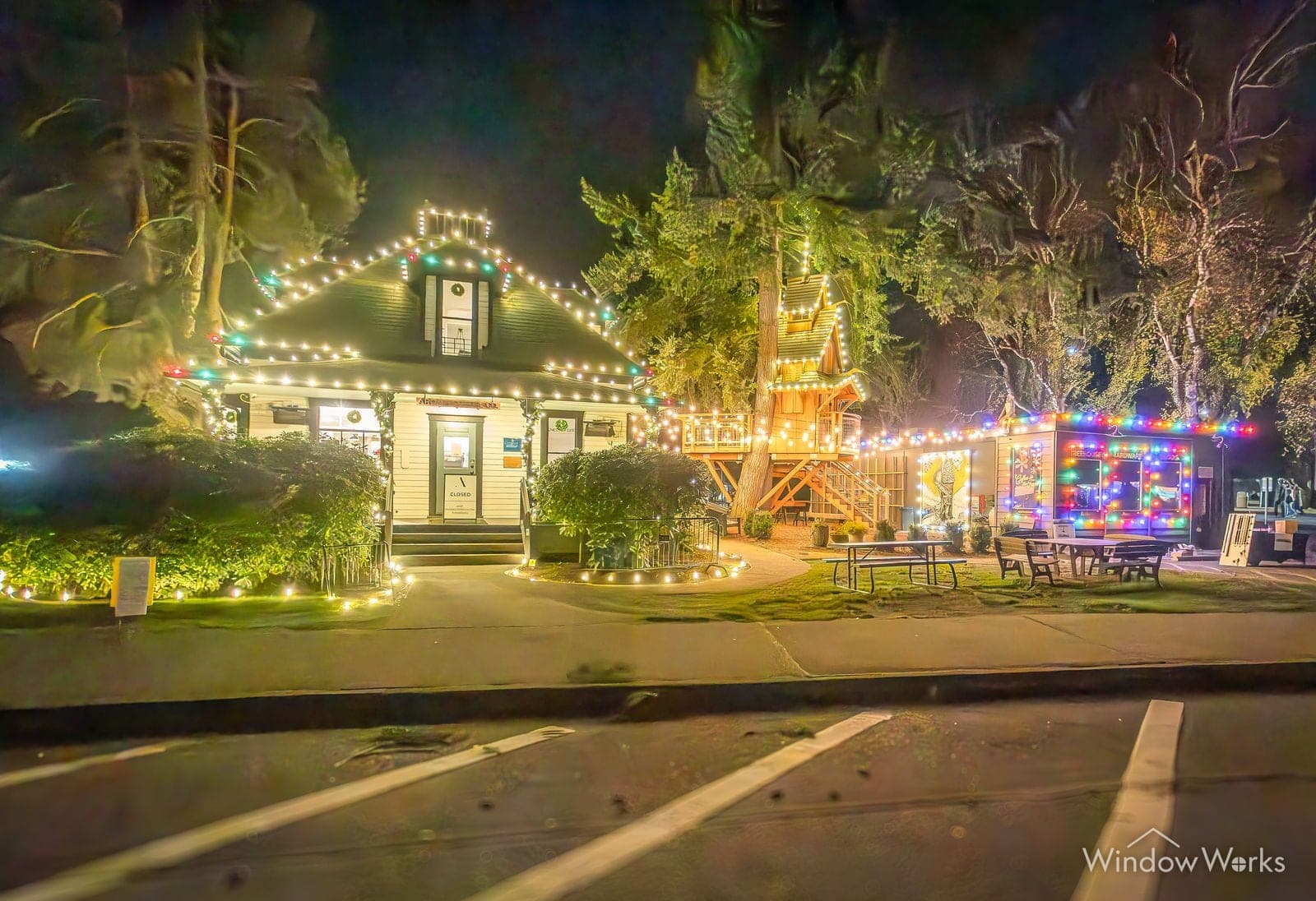A lit property at night, house and two-story playhouse in warm white with paths lit through the garden.