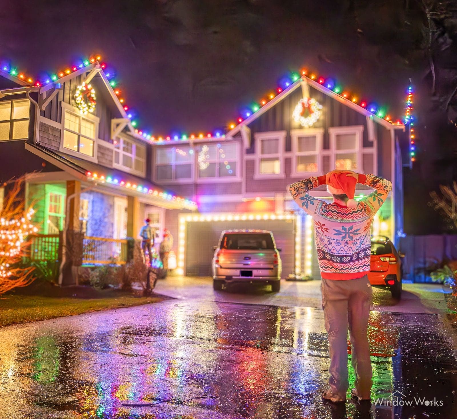 A home with a lit wreath in every window and the owner crossing the drive in a holiday sweater.