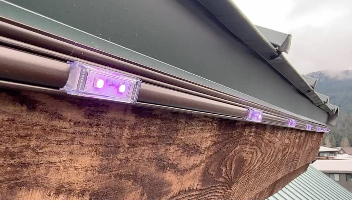 Pebble lights glowing purple in a brown channel on the face of the fascia