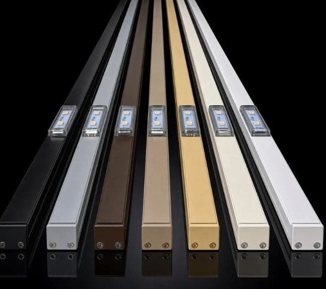 Seven aluminum light tracks side by side, each with a light set in it: black, gray, brown, gray beige, beige, oyster white and white.