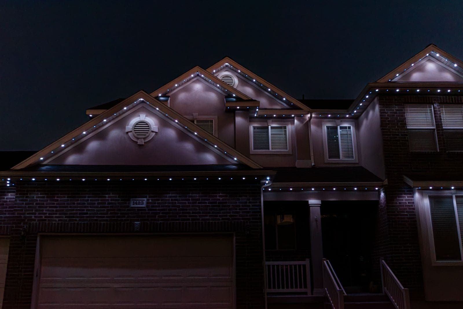 The same home running cool white along every roofline against a black sky.