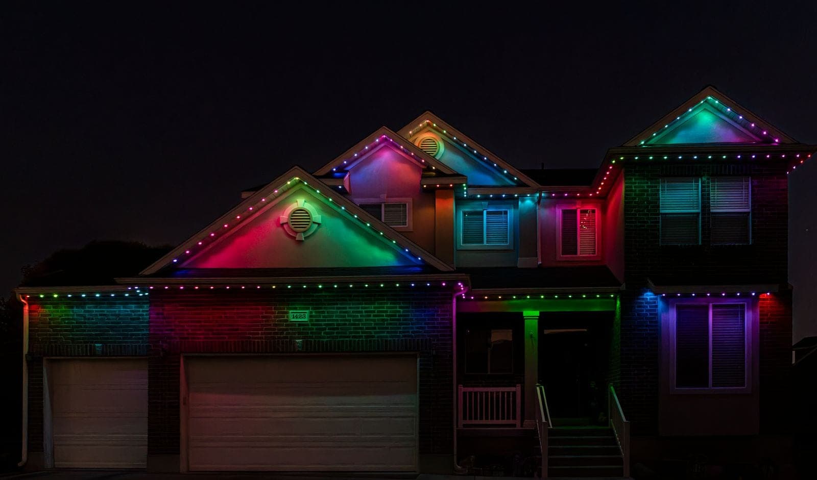 A two-story home running a full-color pattern, every roofline point a different hue and the walls washed magenta, green and teal.
