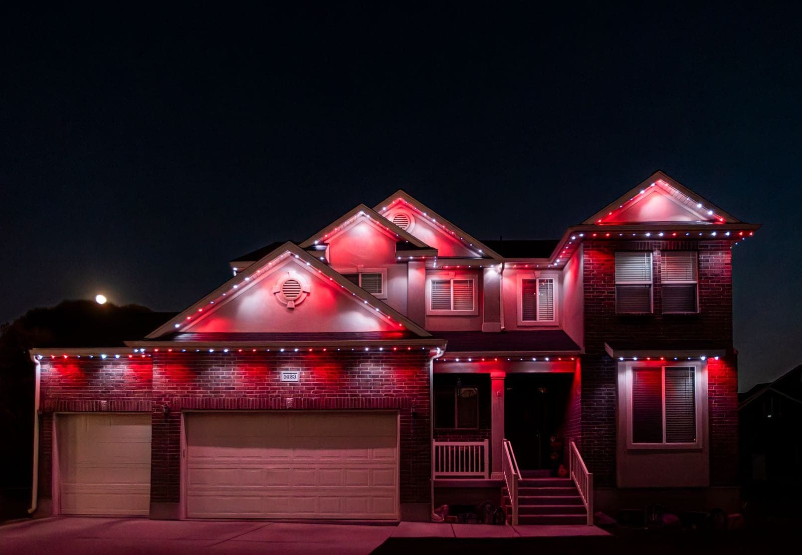 The same home running red across every roofline, the walls washed red and pink under a moonlit sky.