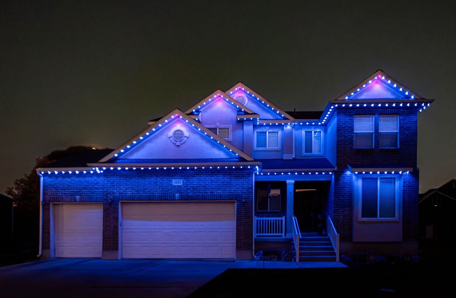 The same home running solid blue across every roofline, the brick and gables washed deep blue.