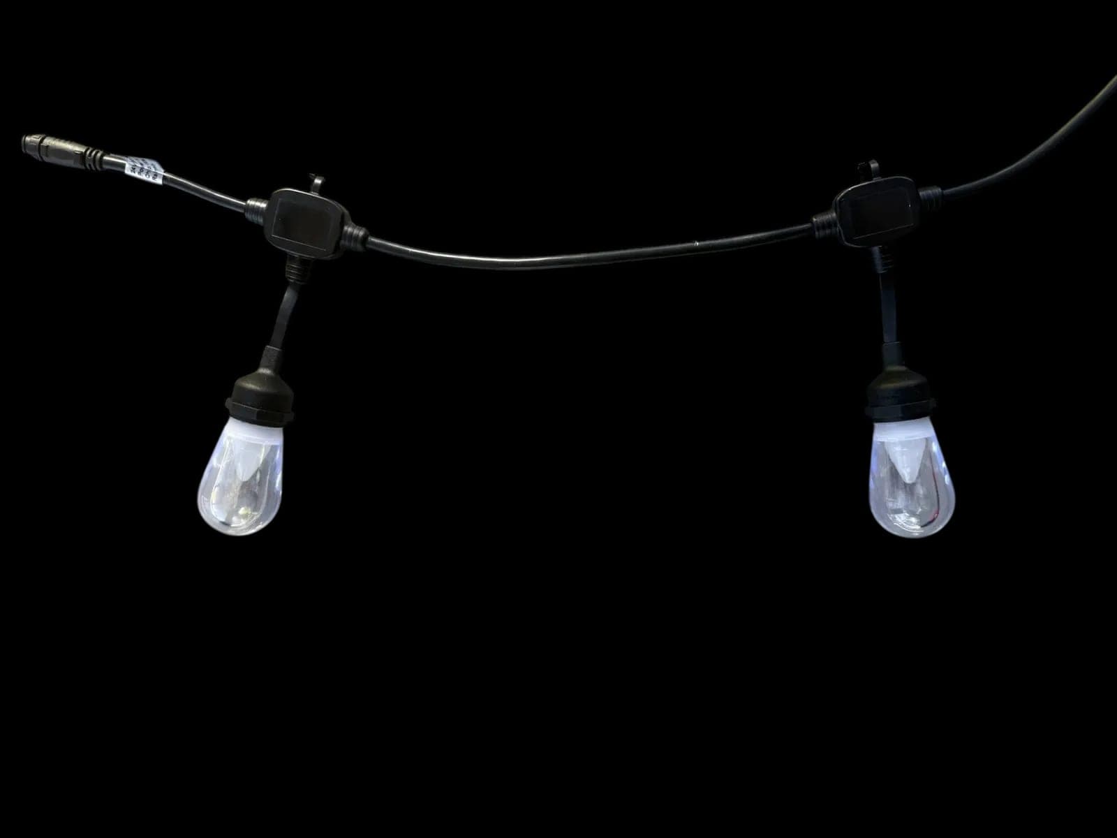A commercial-grade bistro string with weatherproof sockets and clear pendant bulbs hanging along a black cable.