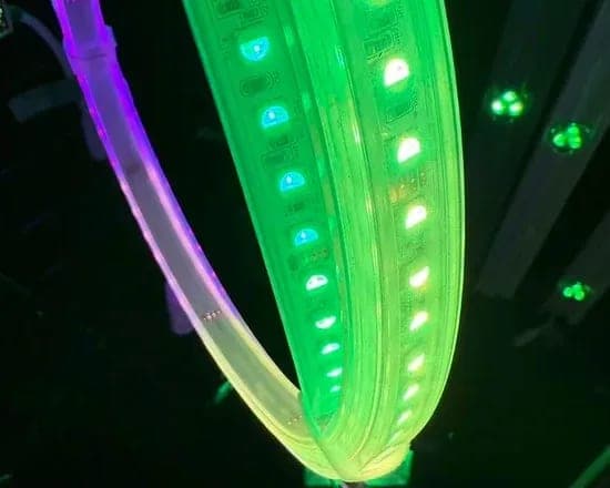 A flexible RGB LED strip curved and lit from magenta through to green.