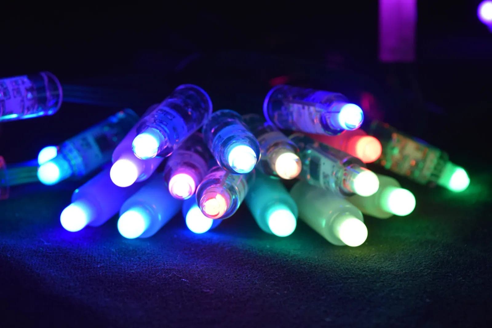 A loose pile of RGB mini bulbs lit blue, red, green and white.