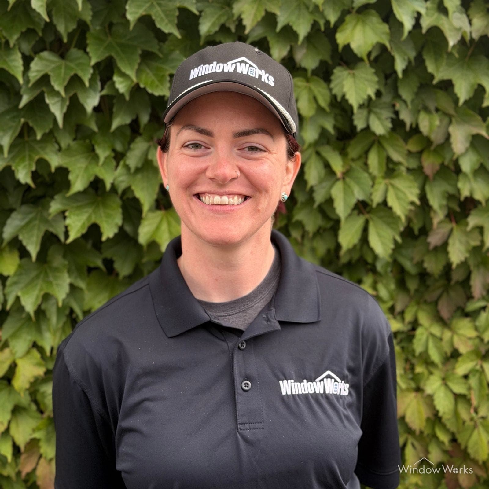 Rye E., Office Manager at WindowWorks, in uniform in front of an ivy wall