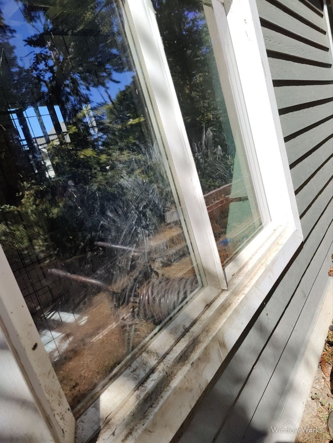 A window thick with dirt and grime, with debris packed into the sill below it.