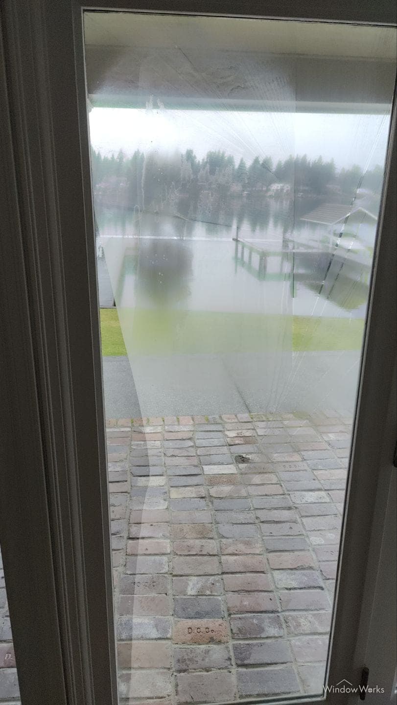 Window film that has failed, gone cloudy, and creased away from the glass behind it.