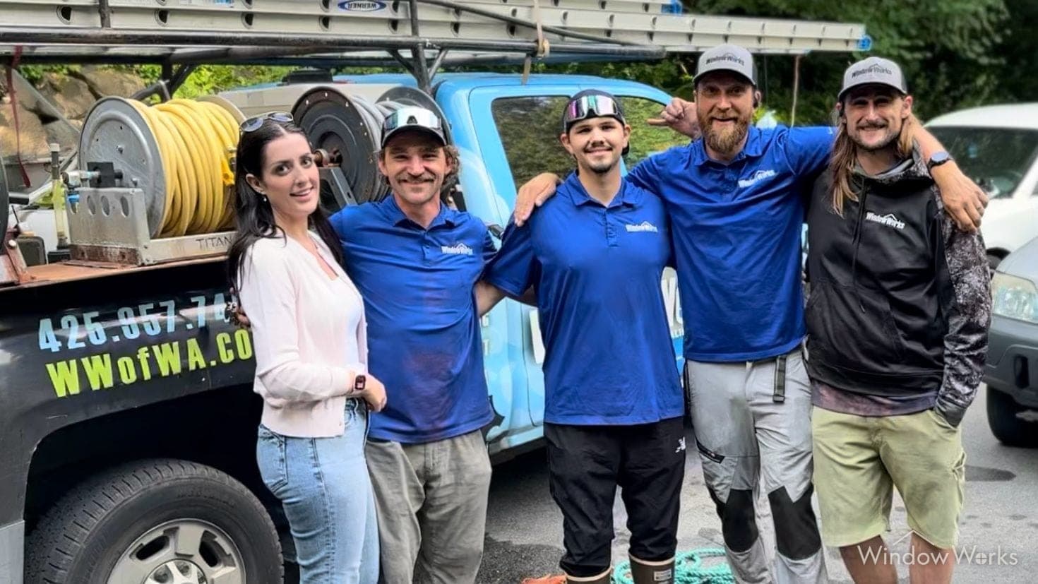 Five WindowWorks technicians with their arms around each other in front of the service truck at the end of a job