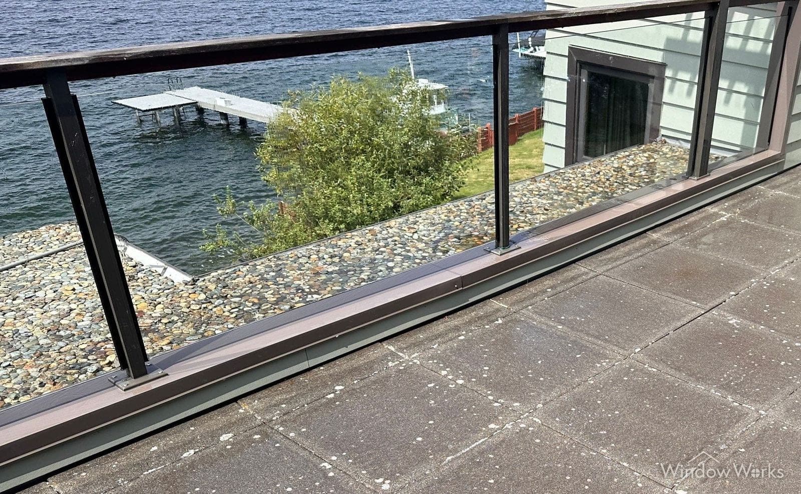 A run of glass deck railing panels cleaned by WindowWorks, overlooking a lake and dock on the Eastside