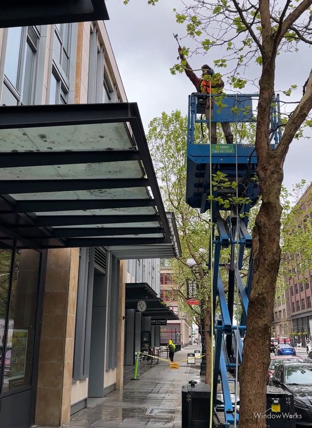 A WindowWorks technician on a lift cleaning glass entry canopies in Pioneer Square