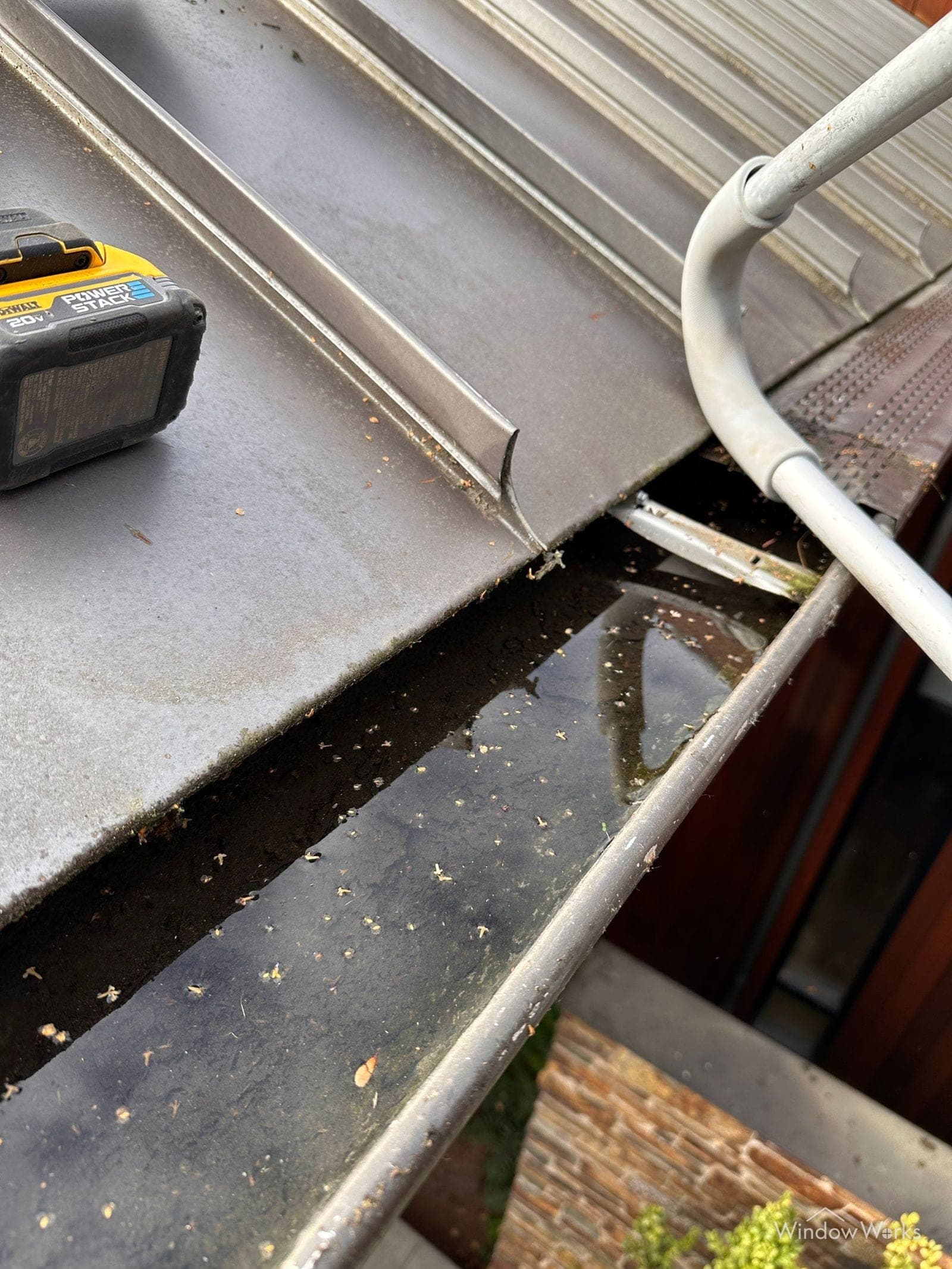 Standing water filling a gutter beside a metal roof where a guard has kept the trough from draining, on an Eastside Seattle home