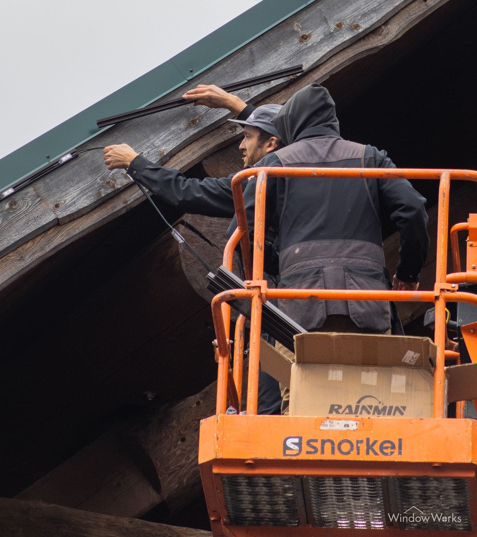 WindowWorks technician on a lift installing a permanent LED lighting track along a home's eave on the Eastside