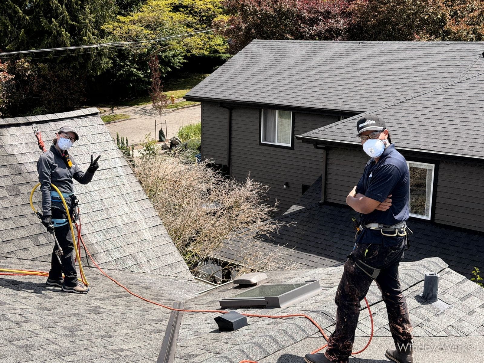 Two WindowWorks technicians in respirators and protective gear on a residential roof