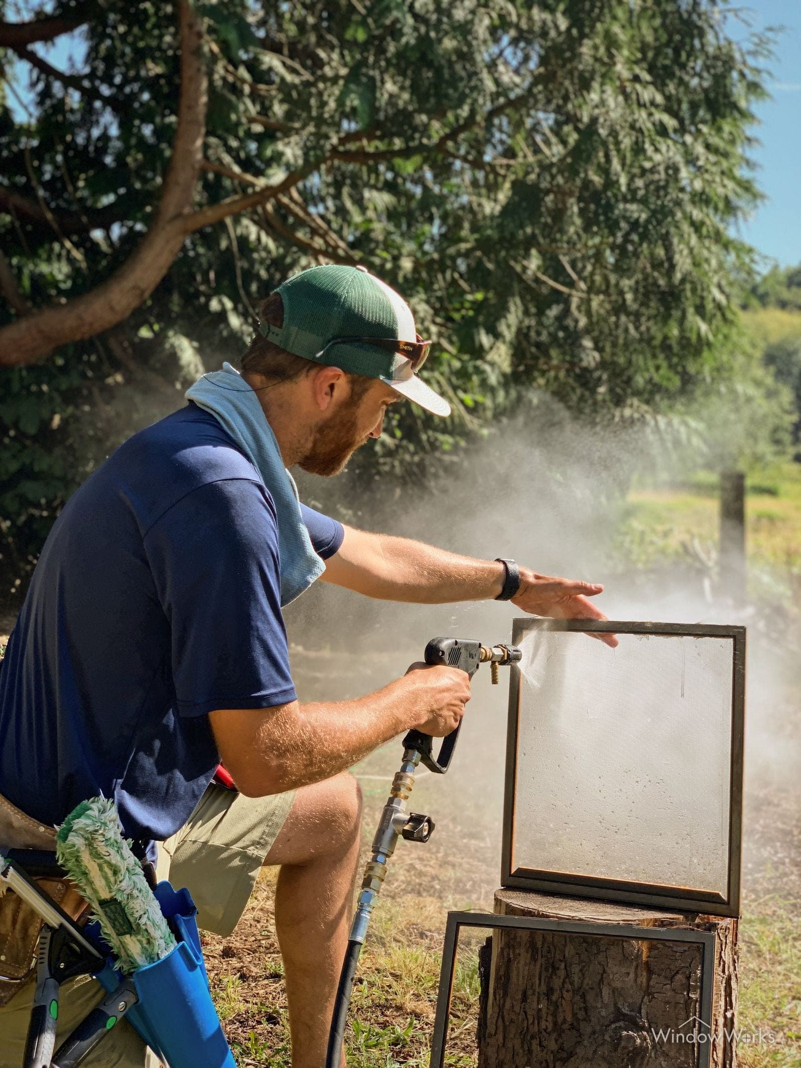 A WindowWorks technician washing a window screen off the frame with a hose gun on an Eastside Seattle property