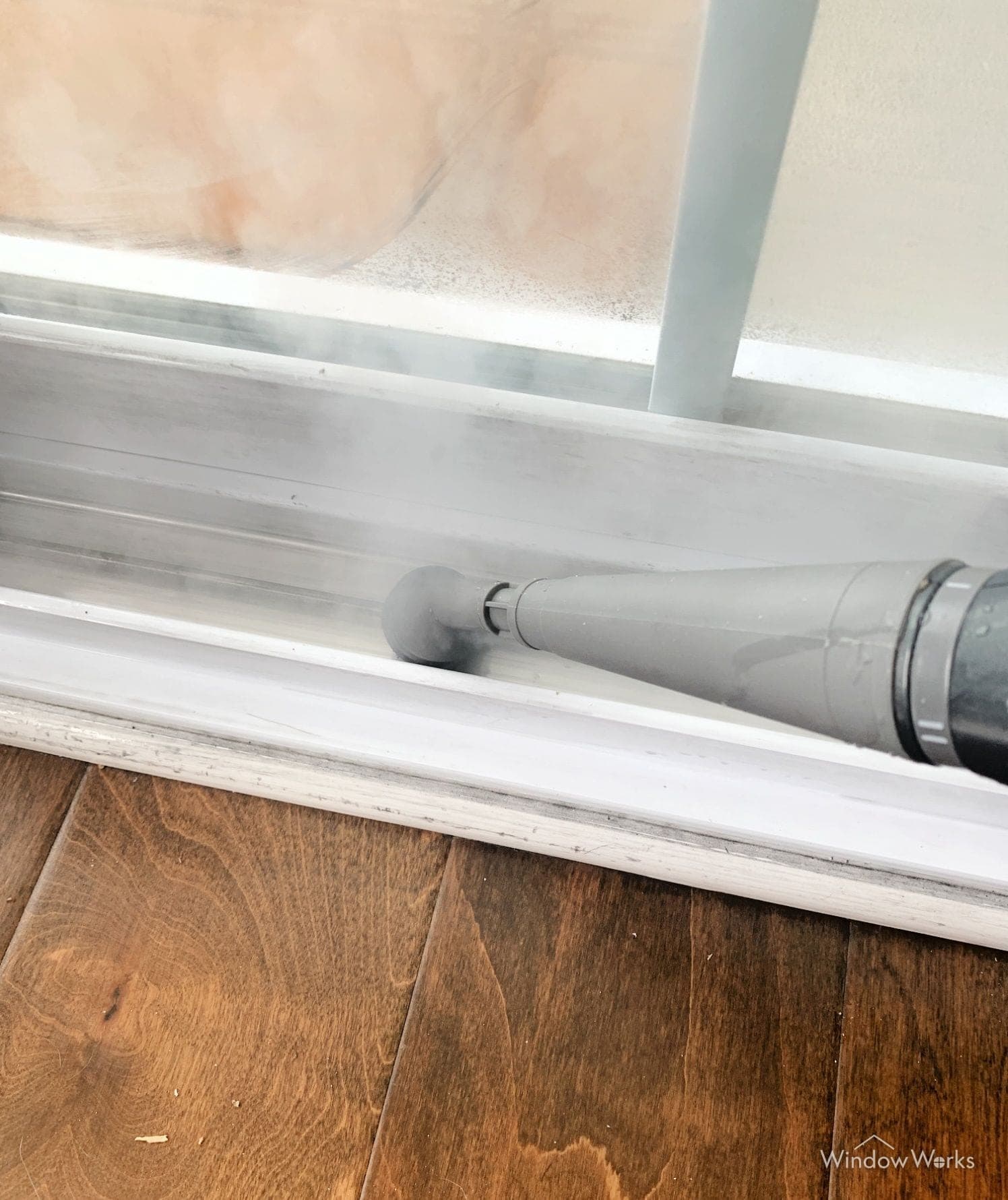 A steam wand clearing packed grime from the track of a sliding glass door on an Eastside Seattle job