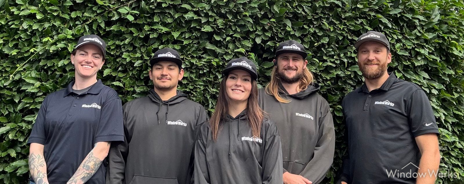 Five members of the WindowWorks team in uniform in front of an ivy wall